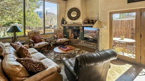 A cozy living room with a fireplace, leather sofas, and a large window overlooking a scenic view. - Uptown Luxury Sedona House @ The Matterhorn Inn (Sedona)