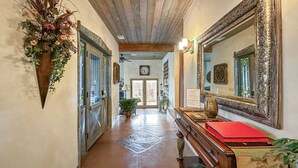 A hallway with wooden floors, a wooden bench, a red folder, a large ornate mirror, and a potted plant. - Uptown Luxury Sedona House @ The Matterhorn Inn (Sedona)