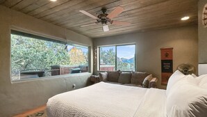 A bedroom with a large bed, two windows, a ceiling fan, and a view of trees and mountains. - Uptown Luxury Sedona House @ The Matterhorn Inn (Sedona)