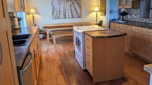 Una cocina con gabinetes de madera, estufa integrada, una mesa de comedor y un ventilador de techo.
