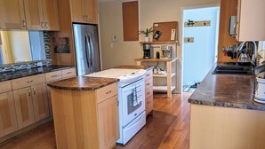 Una cocina moderna con armarios de madera, un refrigerador de acero inoxidable, una estufa eléctrica y un horno empotrado.