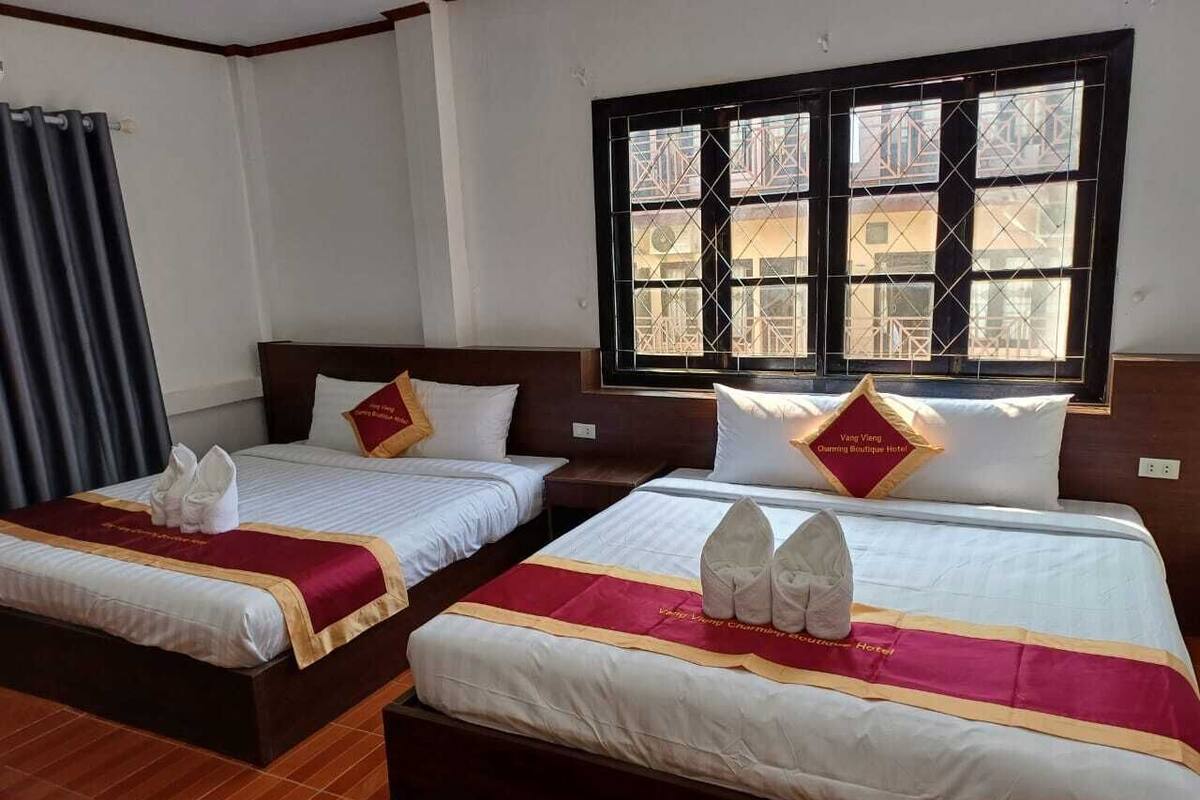 Two double beds with white linens, red and gold bedspreads, and matching pillows.