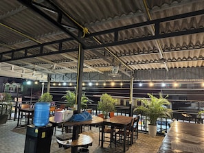 An outdoor seating area with tables and chairs, potted plants, and a water dispenser. - Vang Vieng Charming Boutique Hotel (Vang Vieng)