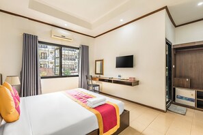 Una habitación de hotel con una cama, televisor, escritorio y armario.