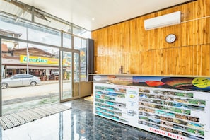 A hotel reception area with a wooden wall, a clock, and a glass door leading outside. - Vang Vieng Charming Boutique Hotel (Vang Vieng)