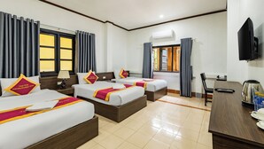 Een hotelkamer met drie bedden, een televisie, een koffiezetapparaat en een airconditioning.