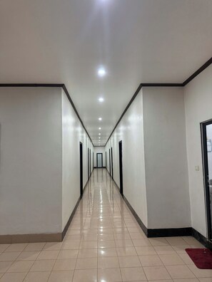 A long, narrow hallway with a tiled floor and white walls, leading to a door at the end. - Vang Vieng Charming Boutique Hotel (Vang Vieng)