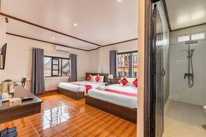 Habitación de hotel con dos camas, un escritorio con tetera y zona de ducha.