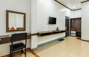 Ein Hotelzimmer mit Schreibtisch, Stuhl, Fernseher und einer Tür.