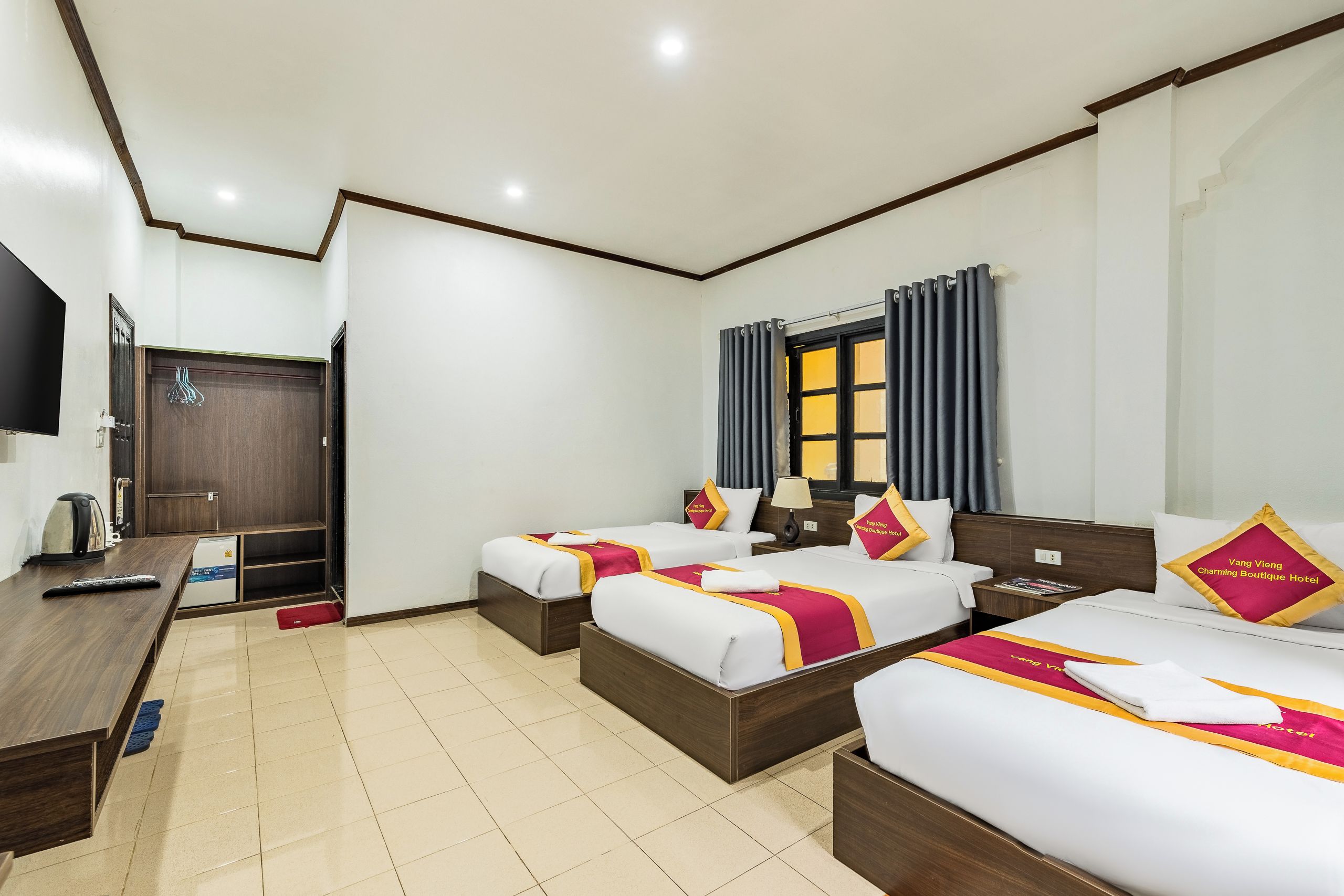 A hotel room with two single beds, a desk, a television, and a wardrobe.