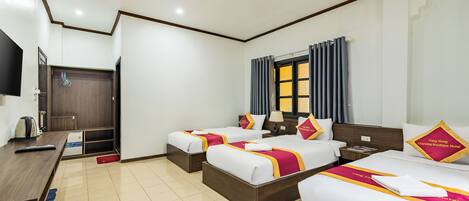 A hotel room with two single beds, a desk, a television, and a wardrobe.