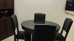 Ein runder Esstisch mit vier Stühlen, einer Chandelier, einem Holzschrank und einem Willkommensschild an der Wand.