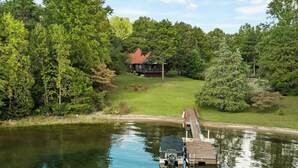 A lake with a dock and a house in the background surrounded by trees. - Kate's Kayak Cove on Lake Keowee! (Seneca)