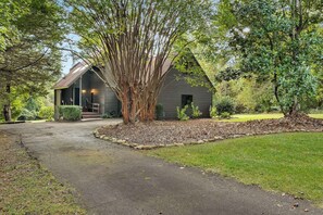A house with a gravel driveway, a wooden deck, and a large tree in front. - Kate's Kayak Cove on Lake Keowee! (Seneca)
