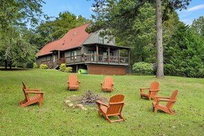Une cabane dotée d’une terrasse, entourée d’une cour verdoyante et d’arbres.