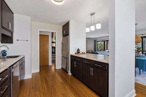 Una cocina moderna con armarios de madera oscura, electrodomésticos de acero inoxidable y piso de madera clara.