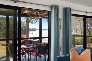 A room with large windows, a dining table with chairs, and a view of a lake. - Kate's Kayak Cove on Lake Keowee! (Seneca)