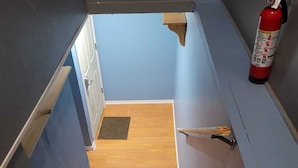 A staircase with a fire extinguisher on the right, a wooden floor, and a blue wall.