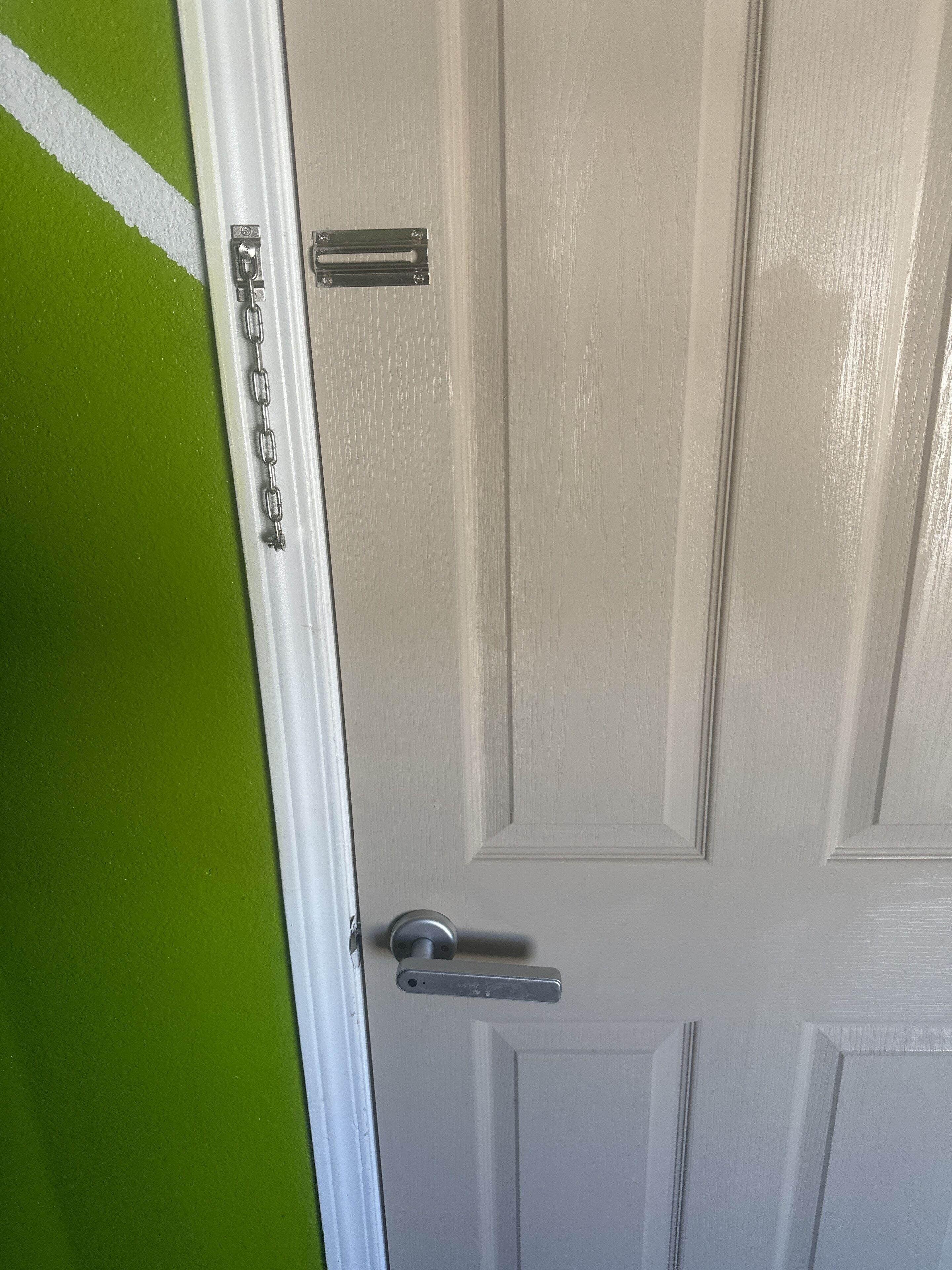 A white door with a silver handle and a chain lock.