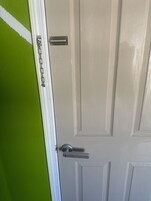 Una puerta blanca con picaporte plateado y una cadena.