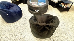 Ein modernes Wohnzimmer mit einem gebogenen Ecksofa, einem Glastisch und zwei Sitzsäcken.