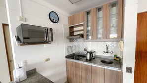 Eine moderne Küche mit Holzausstattung, einer eingebauten Mikrowelle und einer Wanduhr.