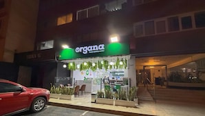 Ein Laden mit einem grünen Schild, auf dem "organa" steht, und einem sichtbaren Gebäudeeingang.