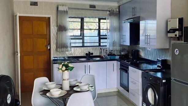 Cocina compacta con comedor, que incluye una mesa para cuatro, lavadora y refrigerador.