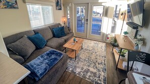 A living room with a grey sofa, blue cushions, a wooden coffee table, and a patterned rug. - Stylish Oasis Tiny Home Pool Hot Tub Pickleball Bullhead City 10 min to Laughlin (Bullhead City)