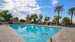 A swimming pool with blue tiles, surrounded by lounge chairs and palm trees. - Stylish Oasis Tiny Home Pool Hot Tub Pickleball Bullhead City 10 min to Laughlin (Bullhead City)