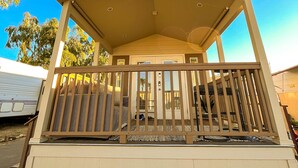 A covered porch with a railing, a door, and a small seating area. - Stylish Oasis Tiny Home Pool Hot Tub Pickleball Bullhead City 10 min to Laughlin (Bullhead City)