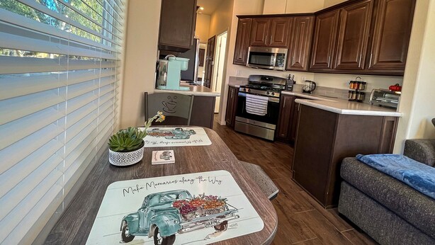 A modern kitchen with dark wooden cabinets, stainless steel appliances, and a breakfast bar. - Stylish Oasis Tiny Home Pool Hot Tub Pickleball Bullhead City 10 min to Laughlin (Bullhead City)