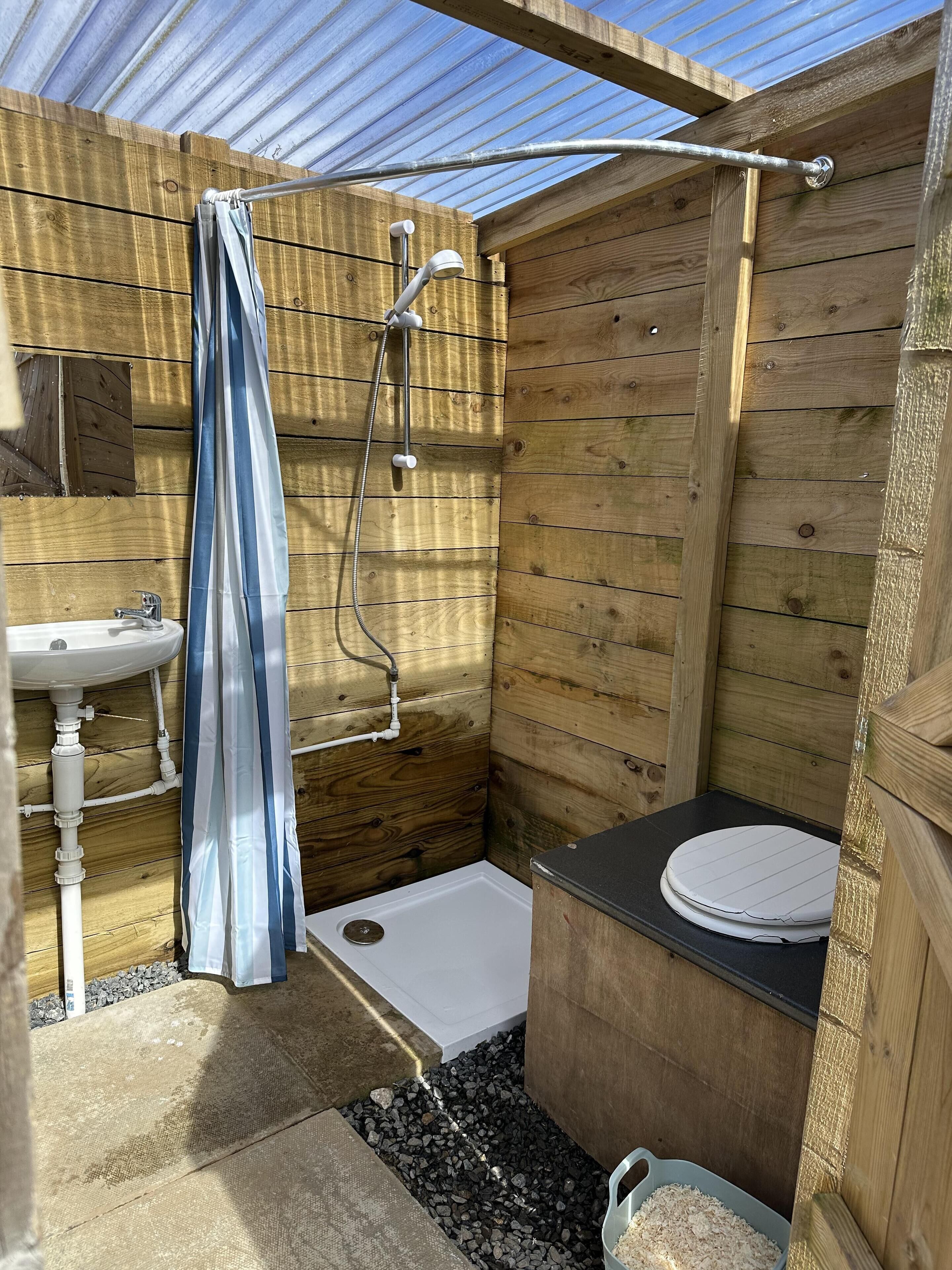 A wooden cabin bathroom with a shower, sink, and toilet.