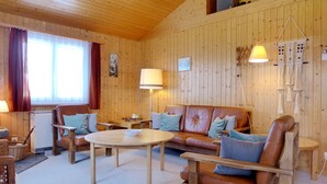 Hyggelig træindretning med sofa, stole, et rundt bord og en lampe.