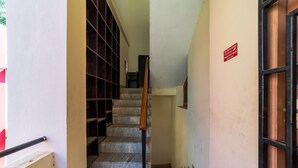 A staircase with a wooden handrail and metal balusters, leading to a landing with a red sign. - Puducherry Residency (Puducherry)