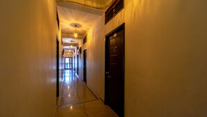 A hallway with a tiled floor, a door on the right, and a light fixture on the left. - Puducherry Residency (Puducherry)