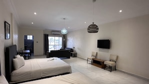 Ein Hotelzimmer mit einem großen Bett, einem Schreibtisch, einem Sessel und einem an der Wand befestigten Fernseher.