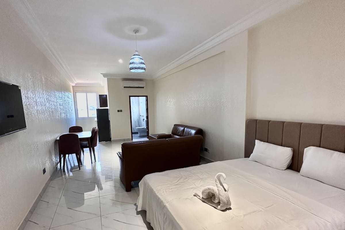Una habitación de hotel con una cama grande, un sofá, una mesa de comedor y sillas.