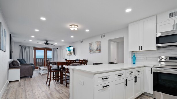 A modern kitchen with white cabinets, a built-in oven, and a dining area with a table and chairs. - La Mirage Condo 237 Beachfront Resort Condominiums with Private Boardwalk (Port Aransas)