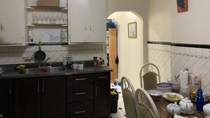 Una cocina con armarios de madera oscura, un fregadero y una encimera con varios objetos como una tetera, tazas y un cubo de basura.