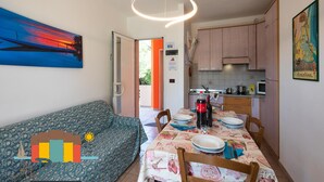 Ein Essbereich mit Tisch für vier Personen, einer Couch und einer Küche im Hintergrund.