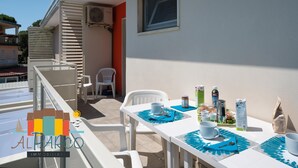 Ein Balkon mit Tisch, gedeckt für ein Frühstück, inklusive Tassen, einer Flasche und einem Einmachglas.