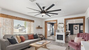A modern living room with a grey sofa, a wooden coffee table, a ceiling fan, and a fireplace.