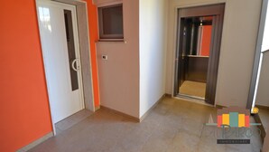 Een gang met een witte deur, een raam en een deur naar een kamer.