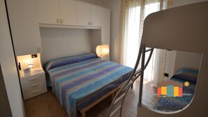 Ein Schlafzimmer mit einem Bett, einem Nachttisch, einem Kleiderschrank und einem Deckenventilator.