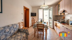Une cuisine moderne avec des meubles en bois, une table à manger avec des chaises et un canapé dans l’espace salon.