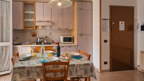 Un coin repas avec une table dressée pour quatre personnes, un four à micro-ondes et des placards en bois.
