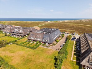 Vista aérea de una zona residencial con casas, un estacionamiento y vistas al mar.