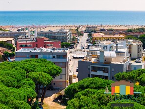 Un pueblo costero con playa, edificios y zonas verdes.