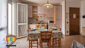 A kitchen with wooden cabinets, a dining table set with plates and glasses, and a hanging light fixture.